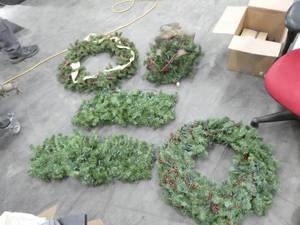 Group of christmas wreaths and greenery all with lights in them