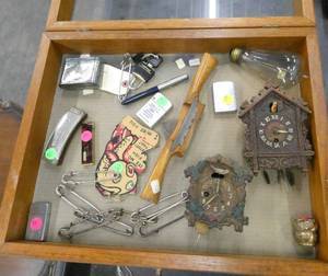 Display box with various vintage items, safety pins, lighters, harmonica, cuckoo clocks