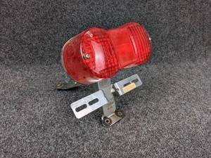 lot 1553 image: NOS - 1973-77 Suzuki GT185 Rear Taillight  Plate Bracket w Lens- Part No. 35710-36110