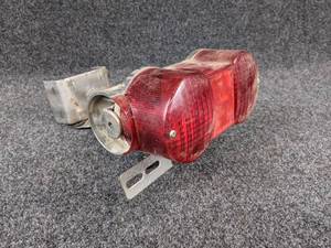 lot 1554 image: NOS - 1971-72 Suzuki TS185 Rear Taillight  Plate Bracket w Lens- Part No. 35710-29611