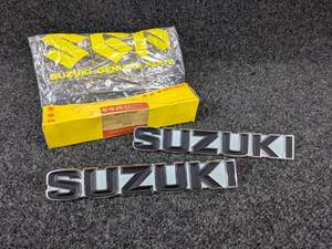 lot 1557 image: NOS - Pair of Vintage Metal SUZUKI Emblems - Part No. 68110-97300, Measure about 7-38 x 1-316 Each