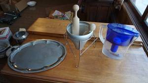 lot 45 image: Round Silver Serving Tray W Gold Trim On Edges---Clear Water Pitcher W Filter & Handle & Royal Blue Cover---Vintage Aluminum Cone Colander Juicer W Stand & 2 Wood Pestles