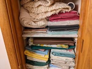 2 shelves of table cloths and sheet...