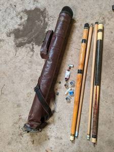 lot 21 image: 2 pool cues in a leather carrying b...