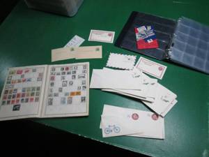 Stamp album partially filled with stamps, post paid envelopes and postcards, coin holder some pages of the stamp album are stuck together from moisture