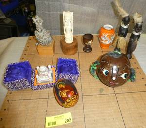 A group of unusual items, wood carved natives, metal knight, a tuskivory looking statue, a coconut character, a mini taj mahal and egg