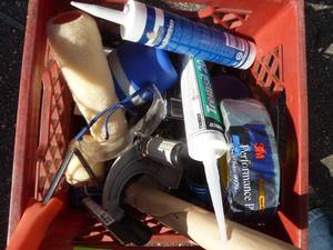 Milk crate of sealant, duct tape, painting supplies
