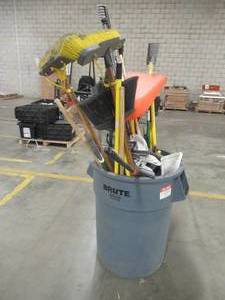 Trash Can Filled with Brooms, Dust Pans, Rakes and More Used in Warehouse.