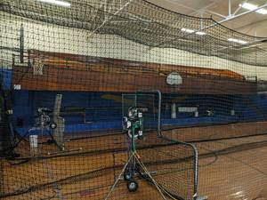 lot 130 image: Gym floor, 2 mounted basketball hoops, wall mats, and bleachers..None of the baseball equipment or nets seen in pics are included  BRING TOOLS, HELP, AND A LADDER TO REMOVE YOUR ITEMS