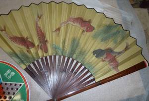 A large vintage chinese folding fan and a chinese checkers game tin full of marbles