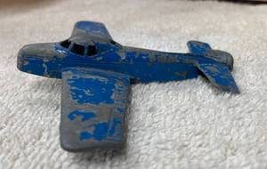 Three Toy Airplanes - Blue Metal Plane with a Bent Tail, Red Plastic Plane with Navy Markings, an Inflatable Submarine