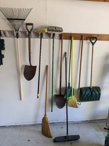Lot of brooms shovels and rakes...