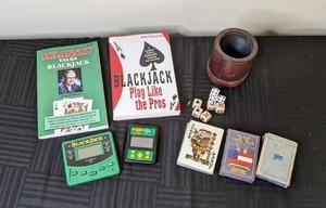 lot 128 image: (2) Black Jack Books, (2) Mini Electronic Black Jack Games, (3) Decks of Cards, Leather Dice Cup, Poker Dice