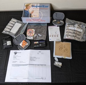 lot 104 image: SuperEar Personal Sound Amplifier, Assortment of Coin Batteries (Various Brands), Phonak Bolero Q Hearing Aid, Battery Tester