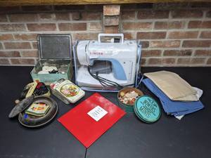 lot 236 image: Singer Simple 3116 Sewing Machine with Manual, Fabric, and Vintage Tins of Buttons, Thread, Elastic, etc.