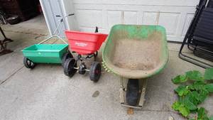 lot 84 image: Outdoor lawn equipment including one pull behind fertilizerseed spreader, one push spreader, one wheel barrel with flat tire