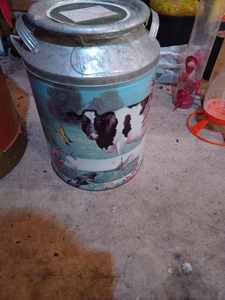 lot 475 image: Milk Can-Shaped Popcorn Tin with Cows Painted on it and a Wicker Basket Full of Pine Cones and Adorned with Christmas