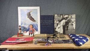 lot 459 image: Folded Flag, Trump Sign, Kissing the War Goodbye Photograph, United States Quarters Collectors Map, Vintage Uncle Sam Coin Bank, Clinton Cat Toy and more  X