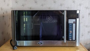 lot 69 image: Oster OGG61101 1.1 cu. ft. 1000W Digital Microwave Oven, Stainless Steel & Black