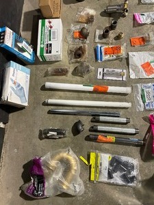 lot 38 image: Miscellaneous Plumbing Supplies, Pipe Fittings, (3) Daltile 8 in. bath corner shelfs, Universal dishwasher connecter, Water heater element, Adjustable flappers, Nylon gloves, Hose adapters and so much more See Pictures