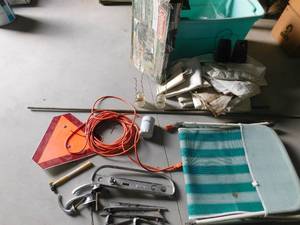Tote of canopy sides, extension cords,lounge chair, speakers, old car parts, coleman camp cooks tove, insulaters, hammer,triangle