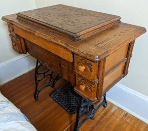 lot 109 image: Antique Treadle Sewing Machine With Cabinet and Attachments