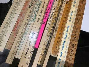lot 34 image: 13 yard sticks various logos and advertisement on them.