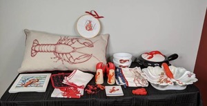 A Collection of Lobster Themed Decor Including Dishes, an Apron, Salt and Pepper Shakers, Magnets, a Throw Pillow and More