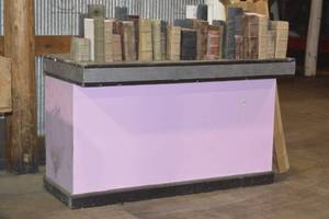 Bar Height pink and black table  with multiple boxes of prop books
