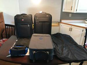 lot 304 image: 2 swiss gear suitcases, 1 without a name,  1 backpack, 1 garmet bag and 1 lunch bag