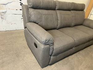 lot 88 image: 3-Seat 84 in. x 32 in. Gray Fabric Reclining Sofa with decorative stitching and fold-down beverage holder.