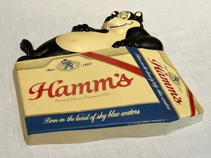 lot 12 image: Vintage Hamms Bear Logo Advertising Plastic Vacuform Black and White Bear Laying on Six Pack of Hamms Beer
