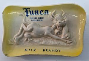 lot 182 image: Vintage Tuaca Demi Sec Liqueur Milk Brandy Advertisment Piece (Chips On Edges) 7 12 x 4 12