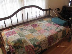 Wood and decorative brass-tone daybed complete with trundle and bedding.