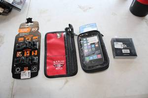 lot 475 image: Lot of (4) Bike Accessories (in original packaging) - Banjo Brothers Phone Wallet, BiKase Handy Andy 5 Phone Case, Oi Bicycle Bell, Anywere Adapter