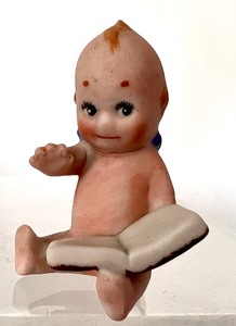 lot 194 image: Antique Kewpie Doll Holding a Book