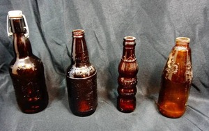 lot 12 image: (4) Vintage Brown Amber Bottles