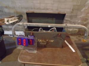 lot 380 image: Older worm drive industrial skil saw in metal box & ladder stabilizer. As shown.