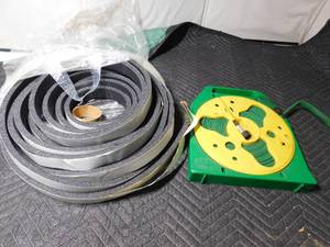 lot 64 image: large roll of weather stripping and retractable garden hose