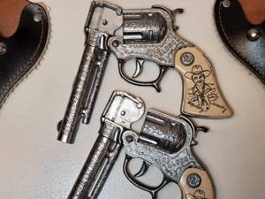 lot 7 image: 1950s Hopalong Cassidy  Double Holster & Cap Gun Set by Wyandotte. The cap guns are unfired, with zero cap residue. The holster is imprinted with a somewhate faded Hopalong, all are in great condition.