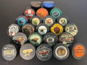 lot 132 image: collection of 26 hockey pucks, incldg. MN Northstars, MN Wild, Chicago Blackhawks, San Jose Sharks 