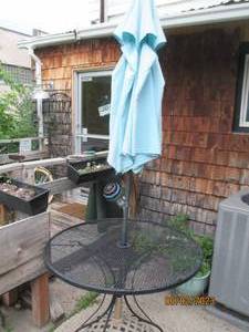 lot 9 image: Round metal patio table with umbrel...