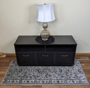 lot 26 image: TV Stand with Storage, Table Lamp, Doily, and Area Rug