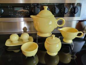 lot 134E image: Lot of Homer-Laughlin Fiestaware Yellow Teapot, Creamer & Sugar Bowl, Salt & Pepper Shakers, Butter Dish Base, and Tripod Bowl