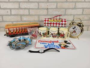 lot 605 image: Lot of Disney Collectables - 1986 License Plate, LORUS Alarm Clock, Watch, Cups, Walt Disney World Train Car and More