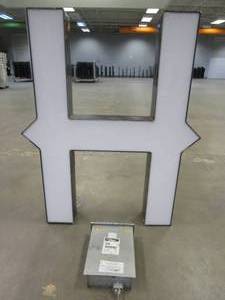 lot 102 image: Lighted Letter H Outdoor Signage With Transformer. Approximate Dimensions 35 x 5.25 x 42.5 Tall - USED FOR RETAIL BRAND MN HOME OUTLET.
