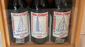 lot 39 image: Shadow Box with 1987, 1988 and 1992 Americas Cup Collectors Pepsi Bottles