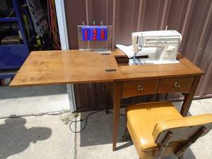 Singer sewing machine in cabinet with chair. As shown.