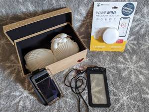 lot 143 image: Wave Mini air quality monitor, GCORD protective cell phone cover, Google Pixal 6A clear case and belt clip,Box of Large Sea Shells