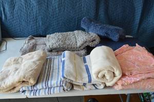 lot 45 image: Full Size pink and orange floral bed spread includes top and fitted sheet and pillow cases.towels- multicolored tan towel, multicolored blue towel, solid tan, New tan throw blanket, bathroom floor matts.